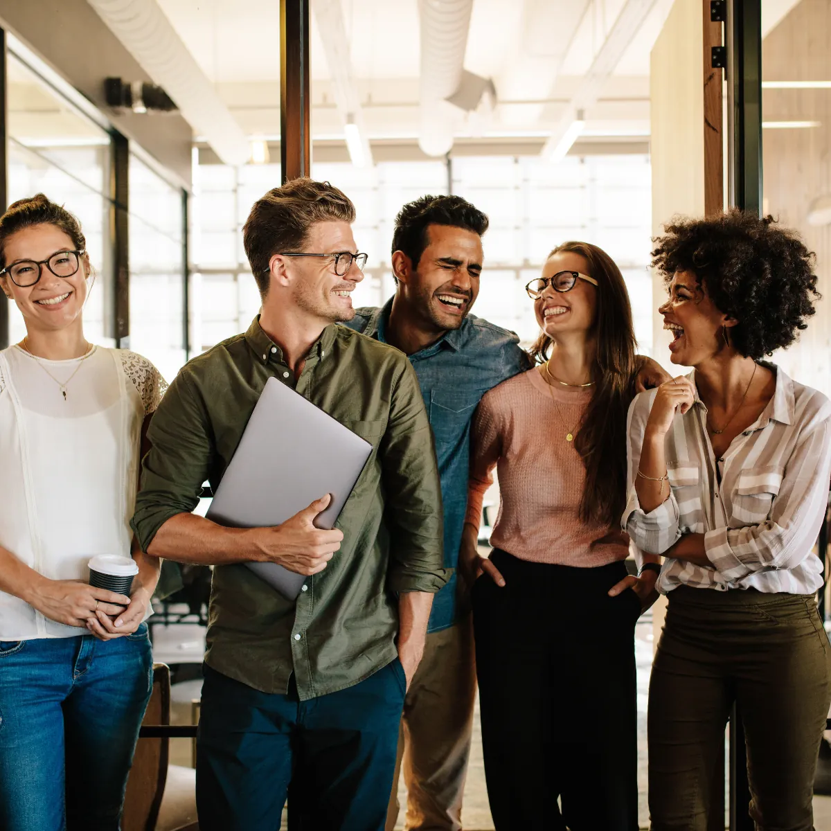 Colegas de trabalho conversando em pé num escritório iluminado